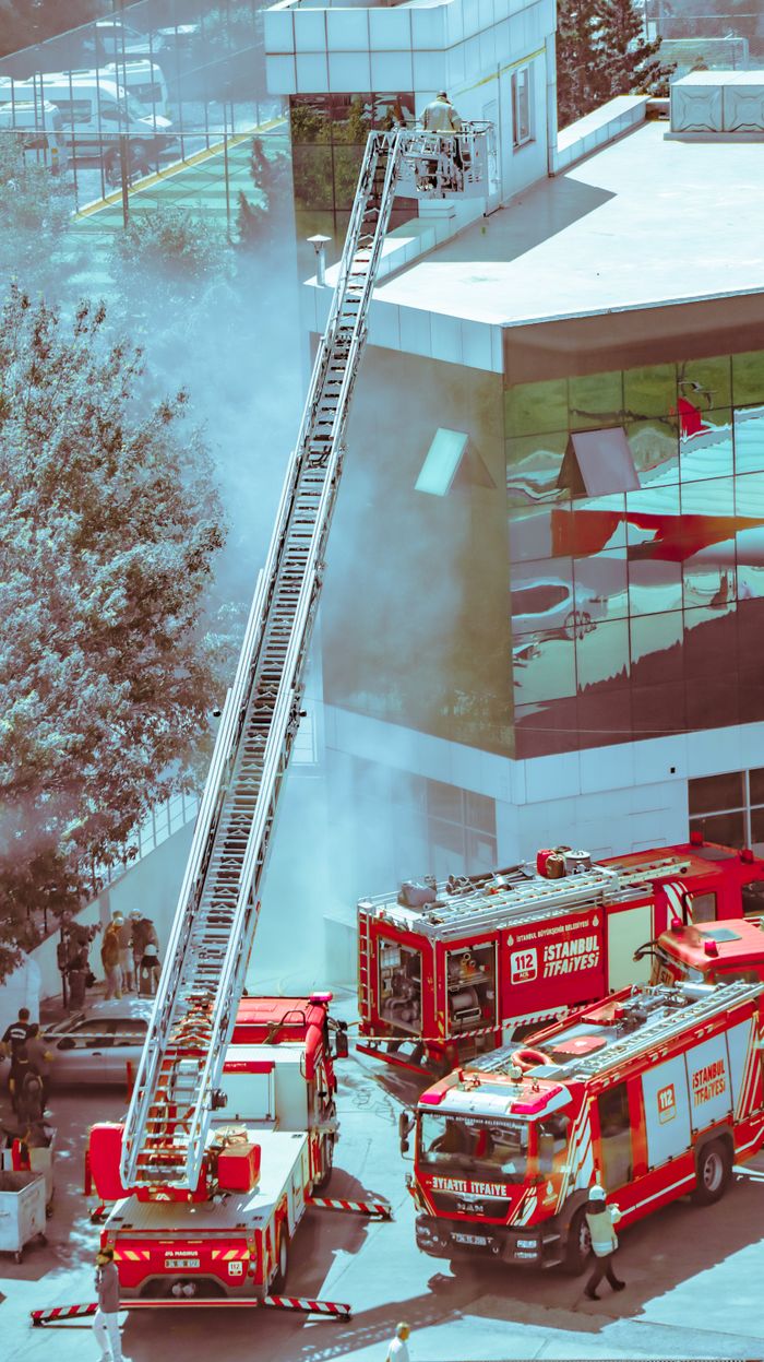 services-01 Firefighters in action using ladder trucks to extinguish a fire in an urban building.