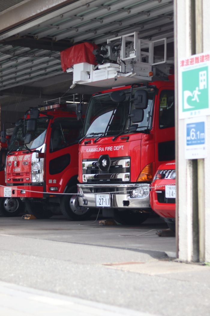 gallery-6 Red fire trucks parked inside Kamakura Fire Department building in Japan, showcasing urban emergency services.