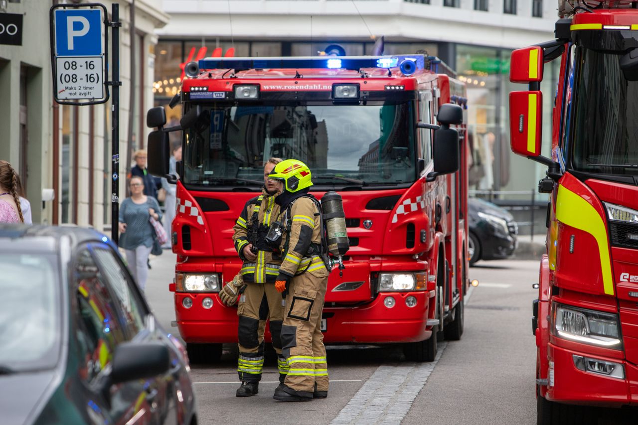 gallery-2 Firefighters in gear standing in front of fire trucks on a city street, ready for emergency response.